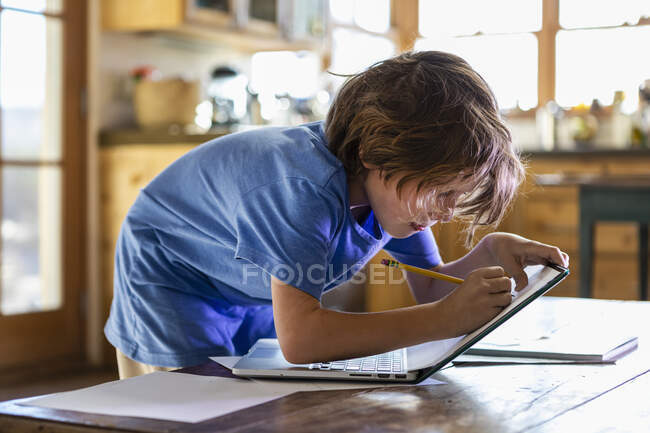 Молодий хлопчик слідкує за своїм ноутбуком — стокове фото
