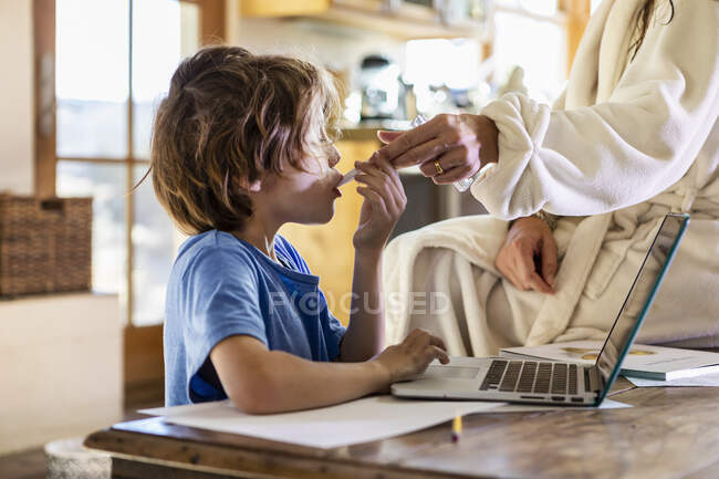 Young boy at home having his temperature taken with a thermometer — Stock Photo