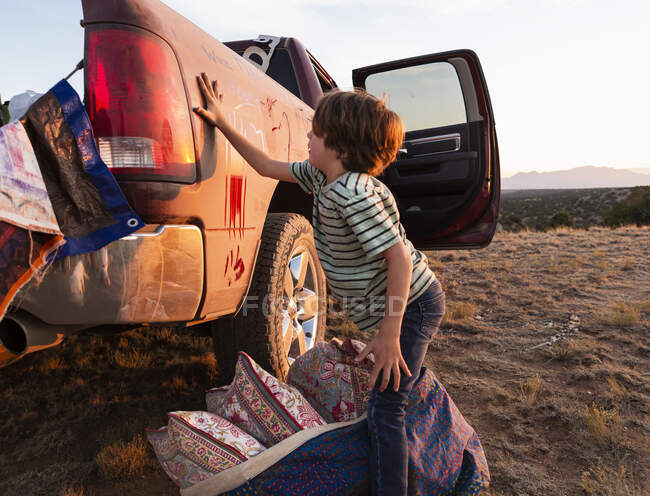 Young boy writing on dirty pickup truck — Stock Photo