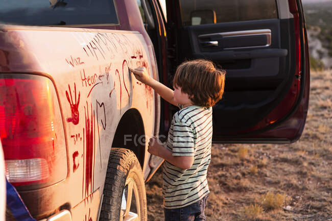 Niño escribiendo en camioneta sucia - foto de stock