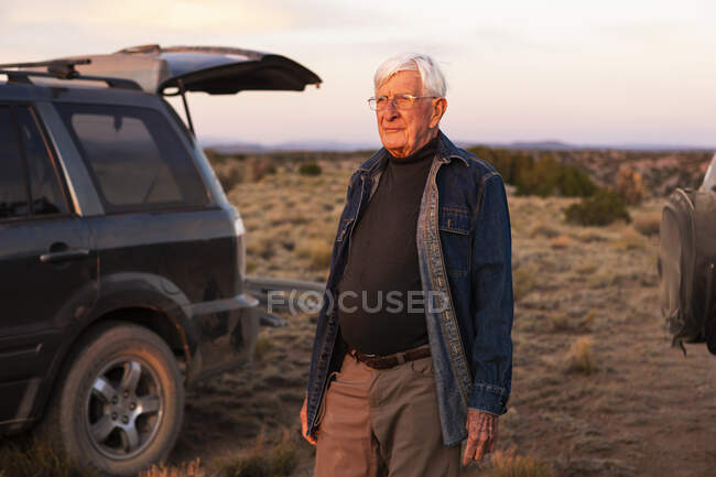 Senior man between SUV cars at sunset, Galisteo Basin, Santa Fe, NM — Fotografia de Stock