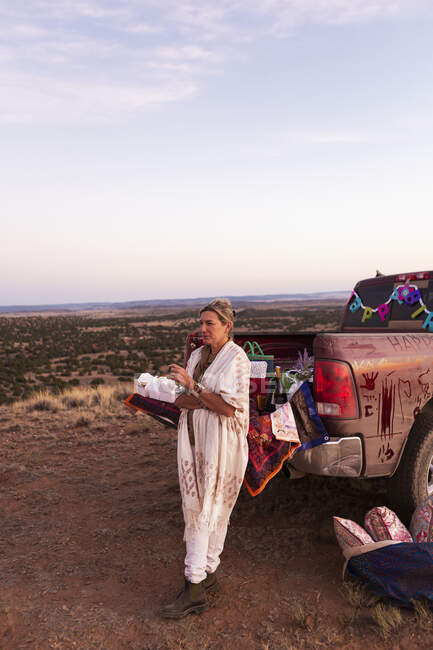 Donna adulta appoggiata al pick-up al tramonto, bacino del Galisteo, Santa Fe, NM. — Foto stock