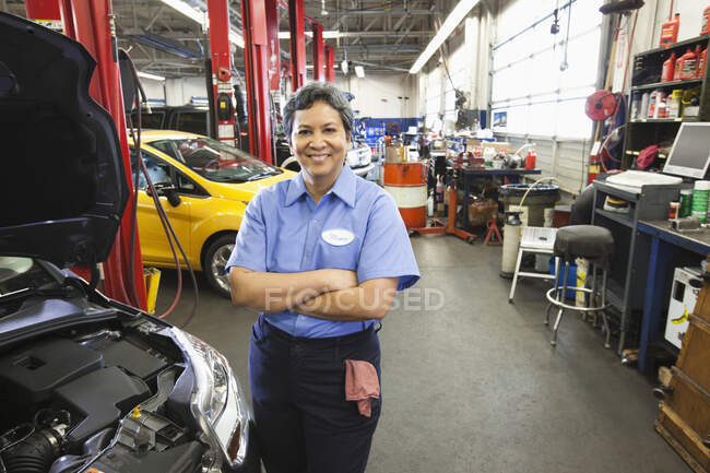 Retrato de mujer mecánica hispana en taller de reparación de automóviles - foto de stock