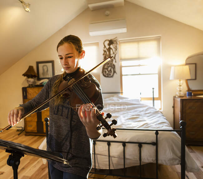 Adolescente tocando su violín en su dormitorio - foto de stock