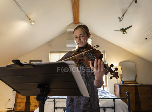 Adolescente jouant son violon dans sa chambre — Photo de stock