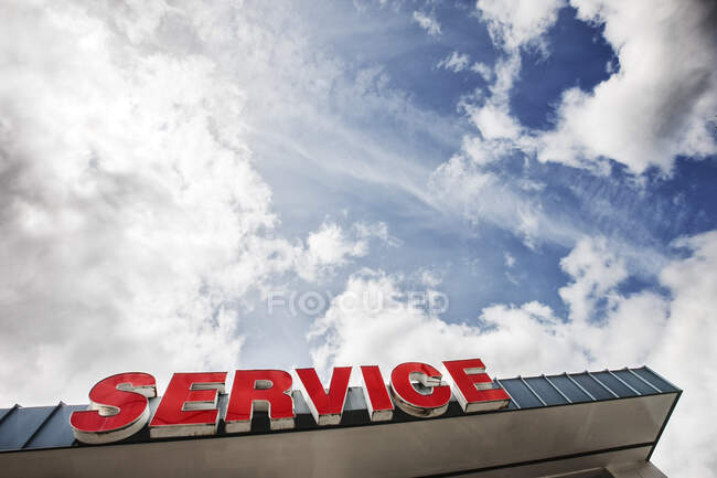 Auto-Service-Schild gegen teilweise wolkenverhangenen blauen Himmel von unten gesehen — Stockfoto