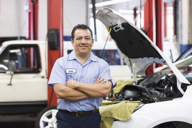 Retrato del mecánico hispano en taller de reparación de automóviles - foto de stock