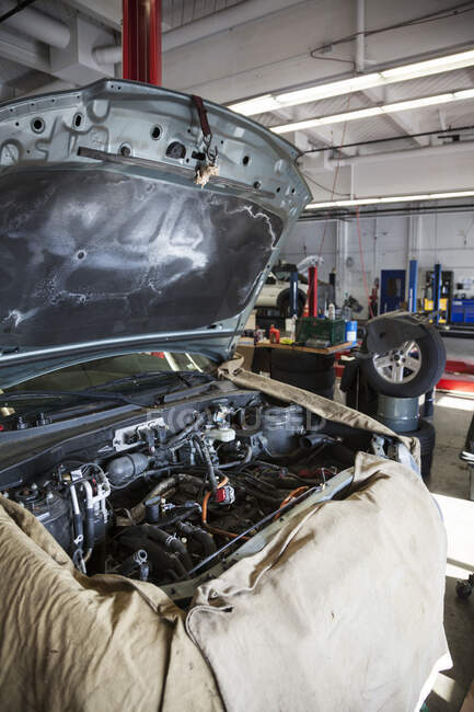 Compartiment moteur ouvert d'une voiture drapée et prête pour un mécanicien dans un atelier de réparation automobile — Photo de stock