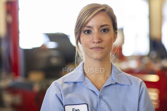 Retrato de mujer joven mecánico caucásico en taller de reparación de automóviles - foto de stock