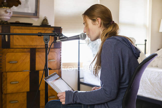 Дівчина-підліток співає в мікрофон у своїй спальні — стокове фото