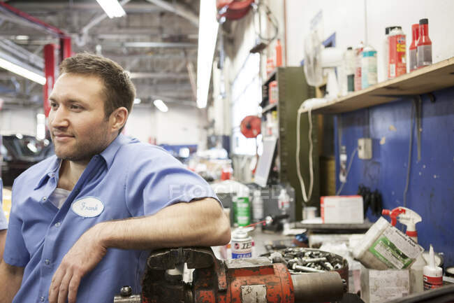 Retrato de un mecánico caucásico sonriente en un taller de reparación de automóviles - foto de stock