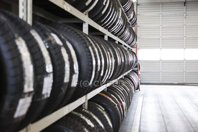Lunga fila di pneumatici nuovi su una cremagliera in un'officina di riparazione auto — Foto stock