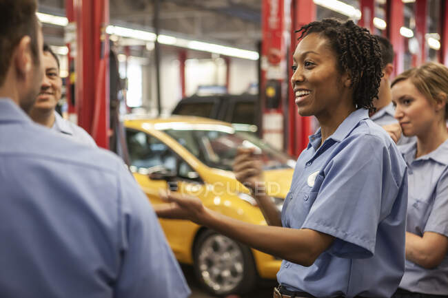 Team of mechanics working on a car discuss a problem in an auto repair shop — Stock Photo