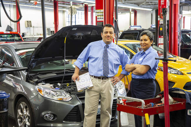 Portrait of owner of auto repair shop talking with female mechanic — Stock Photo