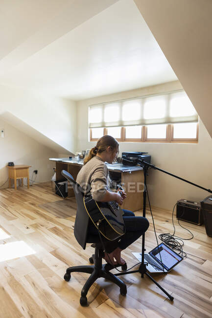 Чотирнадцятирічна дівчинка-підліток грає на гітарі і співає вдома в просторі лофт — стокове фото