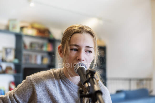 Чотирнадцятирічна дівчинка-підліток грає на гітарі і співає вдома в просторі лофт — стокове фото