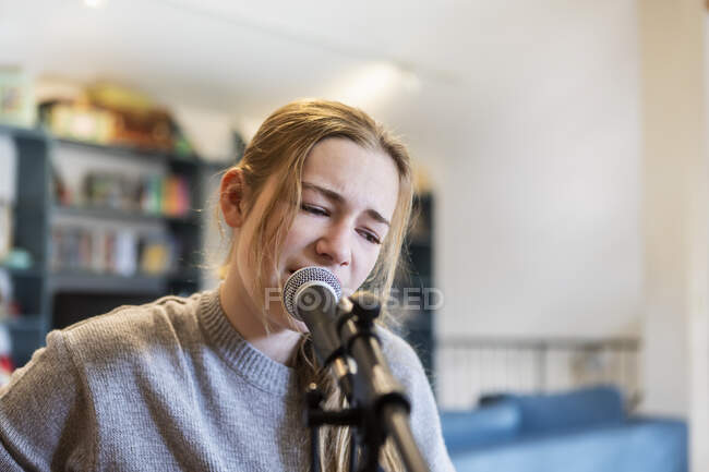 Fourteen year old teenage girl playing her guitar and singing at home in loft space — Stock Photo