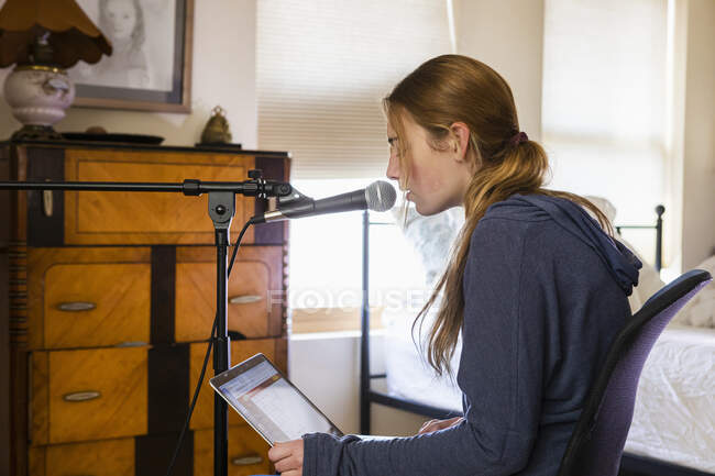 Adolescente chantant dans un microphone dans sa chambre — Photo de stock