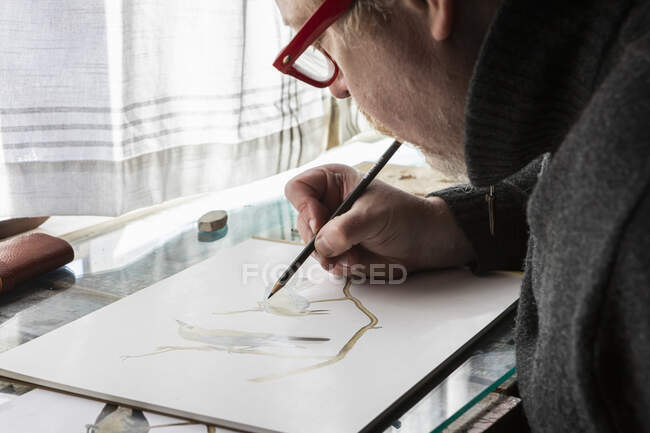 Artista madura no trabalho desenhando sobre papel, um estudo de vida selvagem de pássaros. — Fotografia de Stock