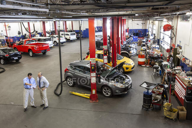 Zwei Geschäftsleute unterhalten sich in Autowerkstatt — Stockfoto