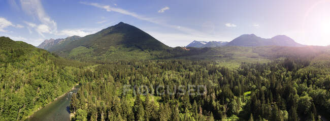 Mountain range and forest in the valley, elevated view of a majestic landscape and a wide river. — Stock Photo
