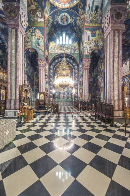A Serbian Orthodox church interior in Ljublijana, murals, painted pillars and walls, and chandelier. — Stock Photo