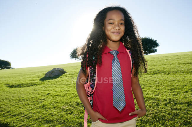 Giovane ragazza di razza mista in camicia rosa e cravatta formale, indossa uno zaino — Foto stock