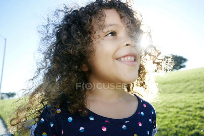 Молодая расовая девушка развлекается на открытом воздухе, кудрявые волосы раздуваются — стоковое фото