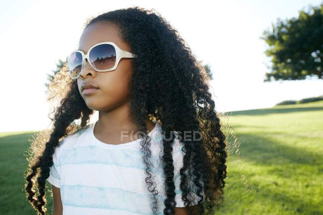 Jovem menina de raça mista usando óculos de sol — Fotografia de Stock