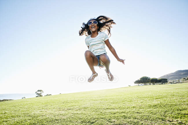 Giovane ragazza di razza mista con lunghi capelli ricci che saltano in aria — Foto stock