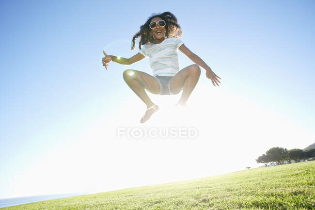 Joven chica de raza mixta con el pelo rizado largo saltando en el aire - foto de stock