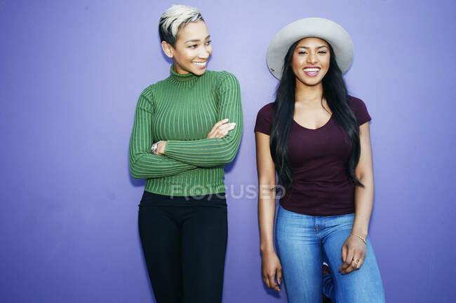 Due giovani donne in piedi fianco a fianco su uno sfondo chiaro — Foto stock