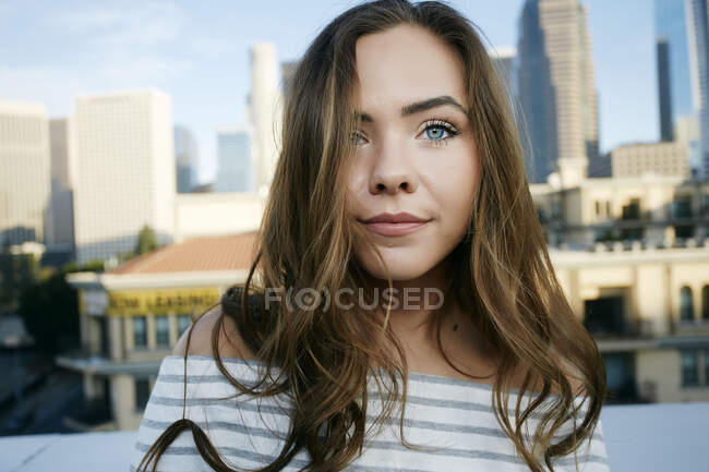 Portrait of young mixed race woman on a city rooftop, skyline behind her. — Stock Photo