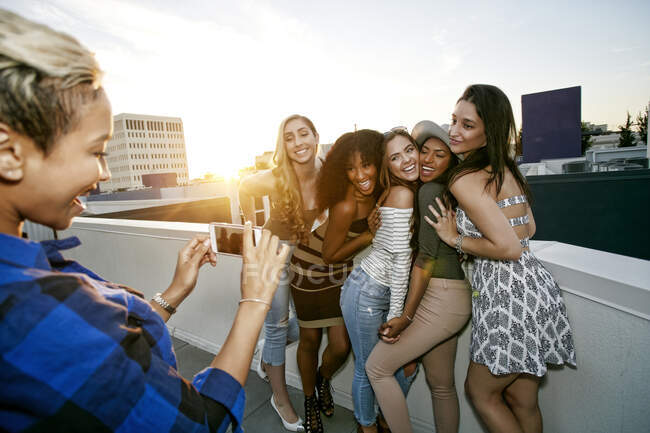 Grupo de mujeres jóvenes de fiesta en una azotea de la ciudad al atardecer - foto de stock