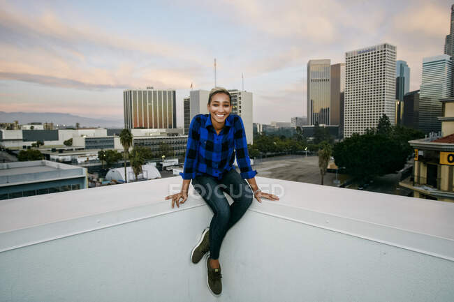 Jovem mulher em um telhado da cidade ao entardecer — Fotografia de Stock