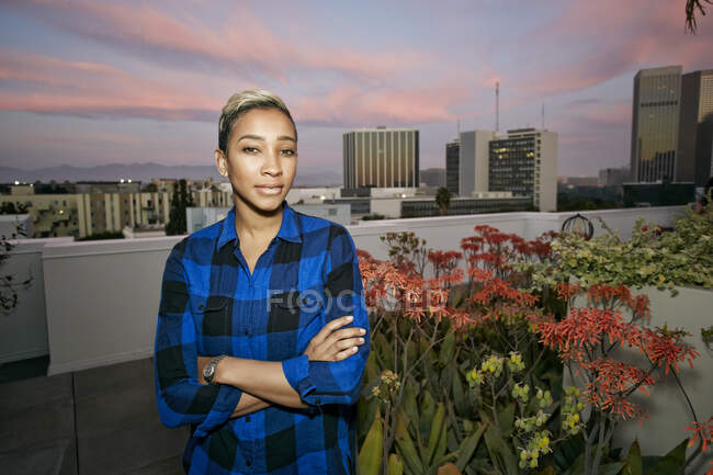 Giovane donna su un tetto della città al tramonto — Foto stock