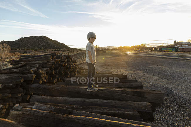 7 year old boy standing alone on railroad ties at sunset — Stock Photo