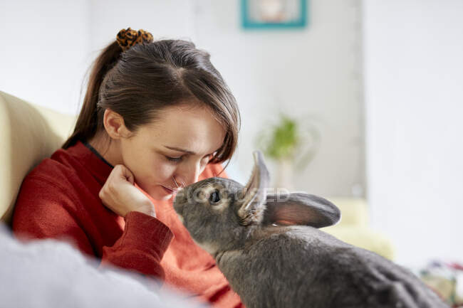 Pet casa coelho nariz a nariz com mulher no sofá — Fotografia de Stock