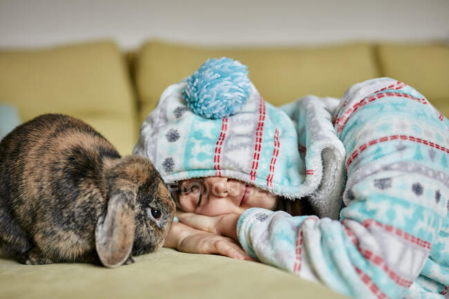 Жінка, що лежить з закритими очима поруч з коричневим домашнім кроликом — стокове фото