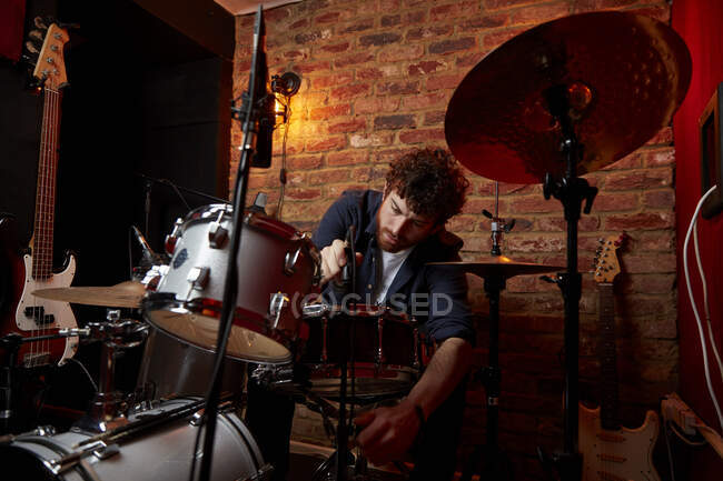 Homem ajustando bateria set no estúdio de música — Fotografia de Stock