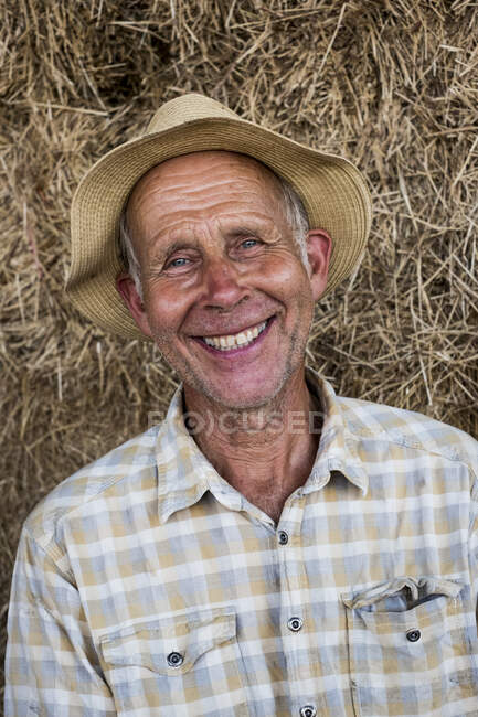 Portrait of smiling man wearing checkered shirt and sun hat, looking at camera. — Photo de stock