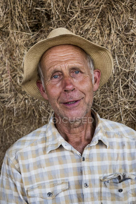 Retrato del hombre sonriente con camisa a cuadros y sombrero de sol, mirando a la cámara. - foto de stock