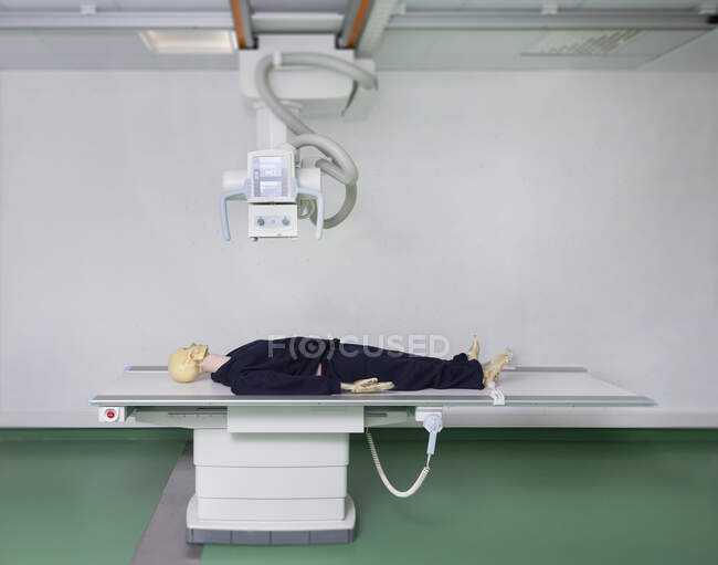 Маннекін лежить на столі під машиною рентгенівського випромінювання в навчальному коледжі — стокове фото