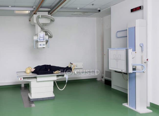 Schaufensterpuppe liegt auf einem Tisch unter einem Röntgengerät in einer Ausbildungsstätte — Stockfoto