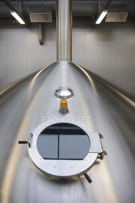 Interior de la cervecería, grandes tanques de almacenamiento de acero para la elaboración de cerveza, escotilla de inspección - foto de stock