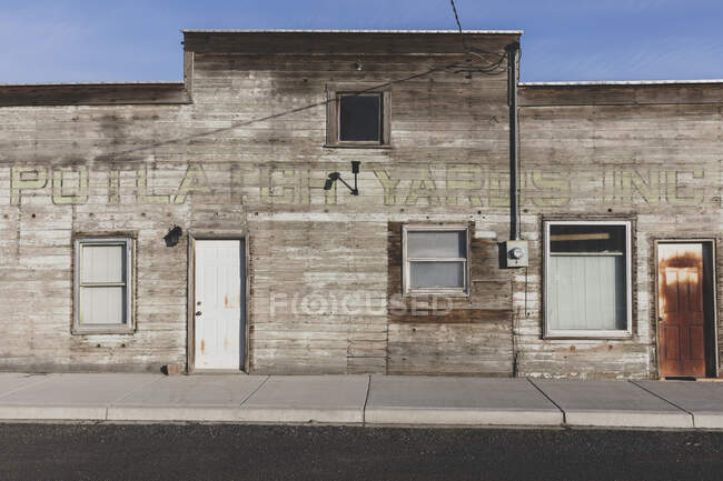 Old wooden building on Main Street, rusted door and boarded up windows. — Photo de stock