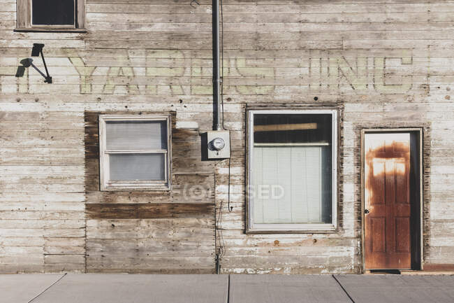 Старое деревянное здание на главной улице, ржавая дверь и заколоченные окна. — стоковое фото
