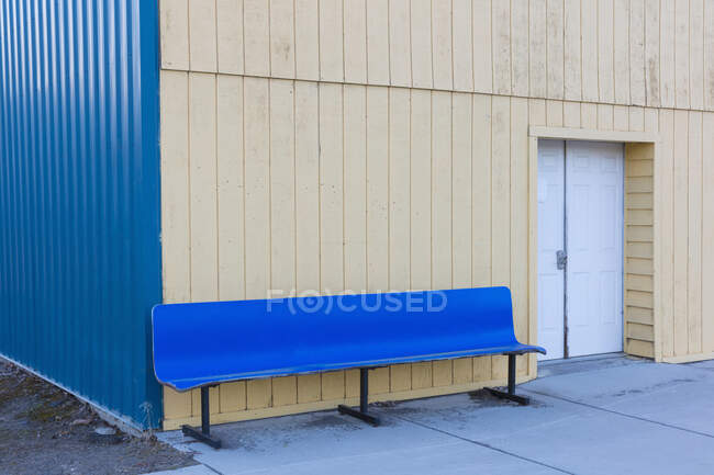 Sozialbau mit geschlossener Tür und leerer blauer Bank draußen. — Stockfoto