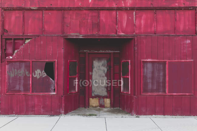 Boarded up building with broken windows on a main street — Foto stock