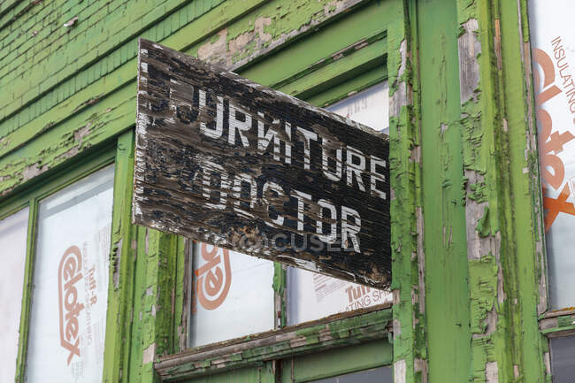 Edificio abandonado en una calle principal, Muebles letrero médico por encima de la puerta principal, taller de reparación - foto de stock